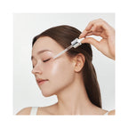 woman applying Essenciel Bright Forte Ampoule with dropper to face