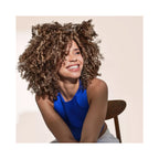 A smiling woman with voluminous, tightly curled brown hair 